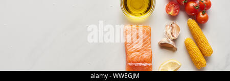 Blick von oben auf die rohen Lachs Steak in der Nähe von Lemon, Mais, Tomaten, Knoblauch, Öl und Pfefferkörner in Schalen auf Marmor tisch, Panorama-Aufnahme ein. Stockfoto