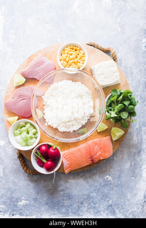 Poke Schüssel sind te letzte Trend in der Lebensmittelindustrie, eine Schüssel mit Gemüse und Lachs auf einem gelb rosa Hintergrund mit riesigen monstera Blatt um. Stockfoto