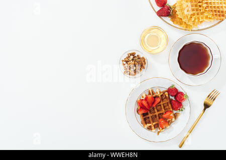 Blick von oben auf die Erdbeeren, Waffeln und Kaffee auf Weiß Stockfoto