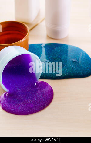 Der Schleim sich. Zutaten für die Helle glitzernde Schleim zu Hause. Violetter Schleim auf eine Tabelle aus Kunststoff Behälter. Stockfoto