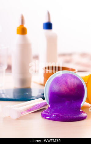 Der Schleim sich. Zutaten für die Helle glitzernde Schleim zu Hause. Violetter Schleim auf eine Tabelle aus Kunststoff Behälter. Stockfoto
