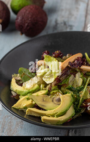 Frisch zubereitete Avocado Salat in schwarz Schüssel auf hölzernen Tisch Stockfoto