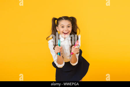 Happy Arts glücklichen kleinen Künstler. Happy girl Holding bunte Markierungen auf gelben Hintergrund. Fröhliches kleines Kind mit glücklichem Lächeln und Stifte. Genießen Sie Kunst und Kunsthandwerk. Stockfoto