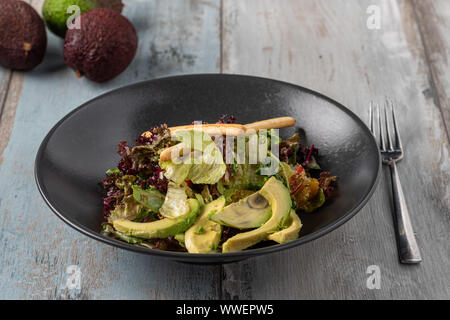 Frisch zubereitete Avocado Salat in schwarz Schüssel auf hölzernen Tisch Stockfoto