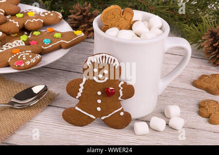 Gingerbread cookies und heiße Schokolade an einem hölzernen Tisch. Tanne im Hintergrund. Weihnachten Konzept. Stockfoto