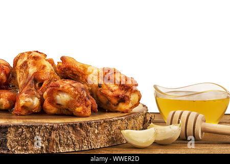 Chicken Wings mit Knoblauchzehen und eine Schale mit frischen Honig auf Holztisch. Auf weißem Hintergrund, kopieren Sie Platz für Ihren Text oder Ihr Bild. Stockfoto