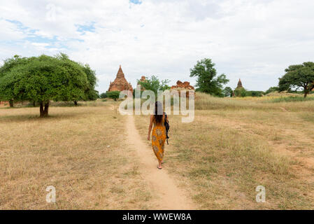 Horizontale Bild der brünette Frau zu Fuß in einer malerischen Blick auf Natur und alte Tempel von Bagan in Myanmar Stockfoto
