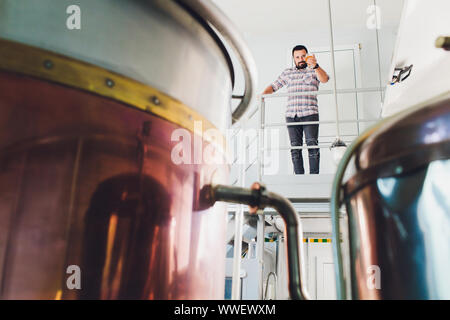 Oktoberfest. Verkostung frisch gebrautes Bier. Brewer hält Glas mit Handwerk Bier. Brauerei Konzept. Mann mit Bier in der Tasse. Alkohol. Männliche Brauer hält Stockfoto
