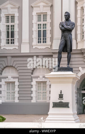 Singapur - März 20, 2019: Schwarz Bronze Statue auf weißen Sockel von Stamford Raffles vor der weißen und grauen Fassade von Victoria Theater. Stockfoto
