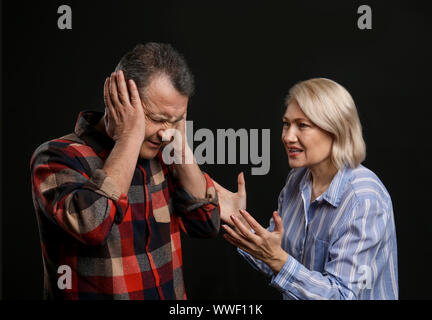 Streitende Paar mittleren Alters auf dunklem Hintergrund Stockfoto