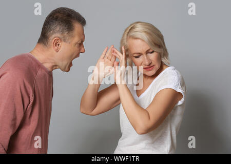 Streitende Paar mittleren Alters auf grauem Hintergrund Stockfoto