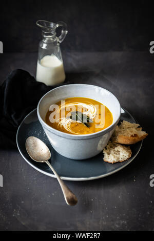 Kürbissuppe mit Sahne und knusprigem Brot auf einem dunklen Moody Hintergrund Stockfoto