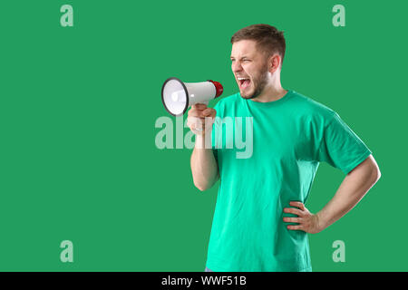 Junger Mann mit Megaphon auf farbigen Hintergrund Stockfoto