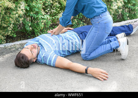 Frau CPR zu unbewussten Mann im Freien Stockfoto
