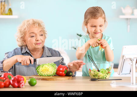 Süße kleine Mädchen mit Großmutter Vorbereitung Gemüse Salat in der Küche Stockfoto