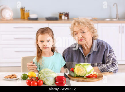 Süße kleine Mädchen mit Großmutter Vorbereitung Gemüse Salat in der Küche Stockfoto