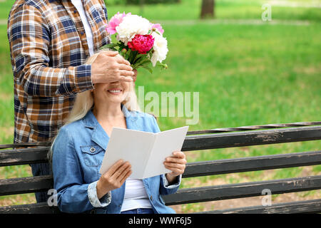 Reife Frau Blumen von ihrem Ehemann in Park Stockfoto