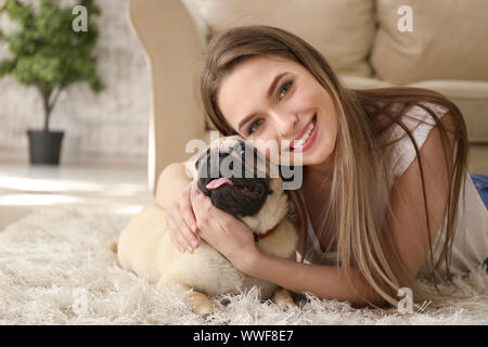 Schöne junge Frau mit niedlichen Mops Hund zu Hause Stockfoto