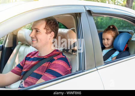 Mann, der mit seiner Tochter in Sicherheit Sitz angeschnallt Stockfoto