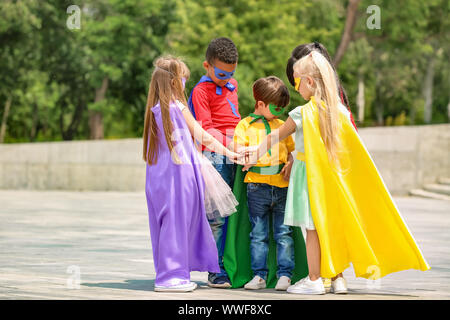 Süße kleine Kinder als Superhelden im Freien gekleidet Stockfoto