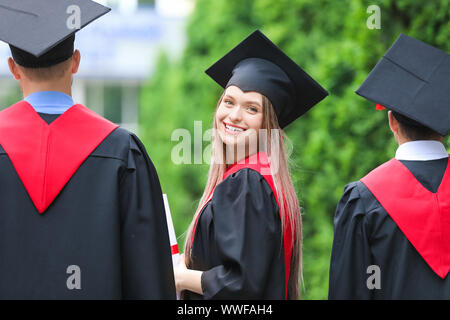 Junge Studenten in Bachelor- Roben im Freien Stockfoto