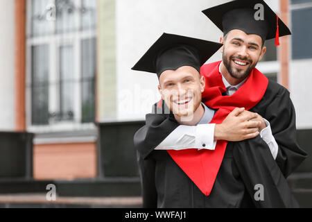 Junge Studenten in Bachelor- Roben im Freien Stockfoto