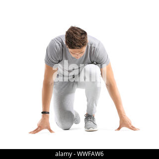 Sportlicher junger Mann in Crouch Startposition auf weißem Hintergrund Stockfoto