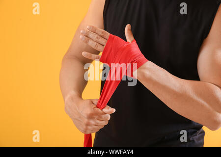 Sportlicher junger Mann Anwendung Armbänder gegen Farbe Hintergrund Stockfoto