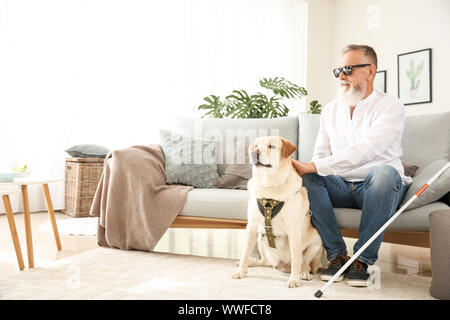 Blind reifer Mann mit Hund zu Hause Stockfoto