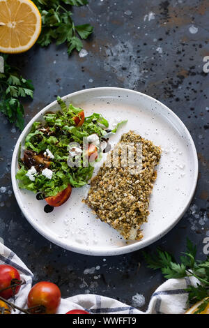 Gebackener Wolfsbarsch würzigen Panade mit frischen Salat. Ein Beispiel für ein ausgewogenes Mittagessen. Das Konzept der richtige Ernährung. Leckere, gesunde und einfache Gerichte. Stockfoto