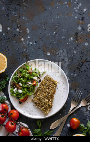 Gebackener Wolfsbarsch würzigen Panade mit frischen Salat. Ein Beispiel für ein ausgewogenes Mittagessen. Das Konzept der richtige Ernährung. Leckere, gesunde und einfache Gerichte. Stockfoto