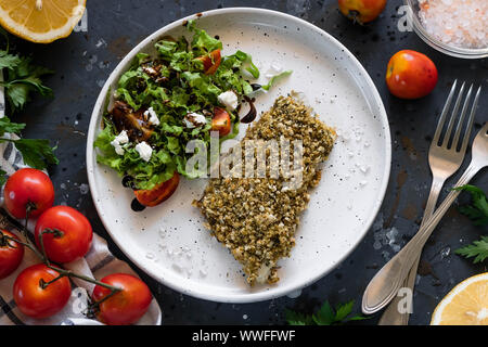 Gebackener Wolfsbarsch würzigen Panade mit frischen Salat. Ein Beispiel für ein ausgewogenes Mittagessen. Das Konzept der richtige Ernährung. Leckere, gesunde und einfache Gerichte. Stockfoto