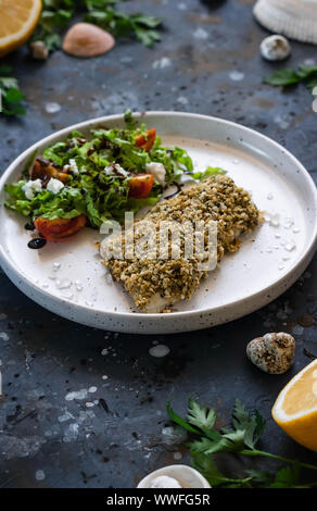 Gebackener Wolfsbarsch würzigen Panade mit frischen Salat. Ein Beispiel für ein ausgewogenes Mittagessen. Das Konzept der richtige Ernährung. Leckere, gesunde und einfache Gerichte. Stockfoto