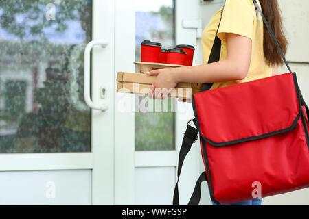 Mitarbeiterin der Food Delivery Service warten auf Kunden in der Nähe der Tür geschlossen Stockfoto