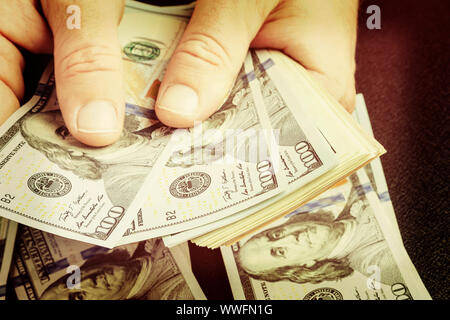 Kaukasische Hände zählen Dollar Banknoten. Zählen oder die Ausgabe usd Geld Banknote, Business und Finanzen Konzept. Getönt Stockfoto