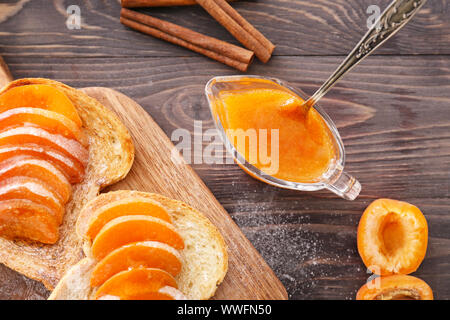 Scheiben Brot mit lecker Aprikosen Konfitüre auf hölzernen Tisch Stockfoto