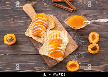 Scheiben Brot mit lecker Aprikosen Konfitüre auf hölzernen Tisch Stockfoto