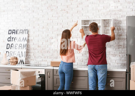 Junges Paar hängende Regal an der Wand in Ihrem neuen Haus Stockfoto