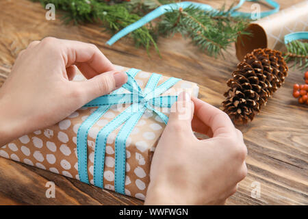 Frau binden Schleife auf Weihnachten Geschenk Box am Tisch, Nahaufnahme Stockfoto