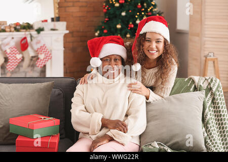 Portrait der afroamerikanischen Frau und ihre Tochter in Santa Hüte zu Hause Stockfoto