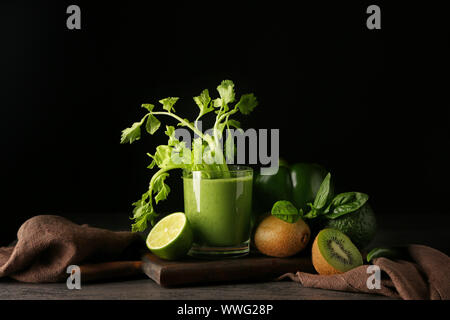 Glas leckeren Smoothie mit Zutaten auf den Tisch gegen den dunklen Hintergrund Stockfoto