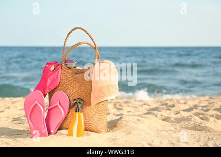 Beutel mit flip-flops, Badebekleidung, Handtuch, Sonnenbrille und Kosmetik auf Sand Strand Stockfoto