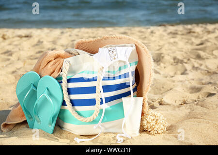 Beutel mit Flip-flops, Badeanzug, Hut, Handtuch und Kosmetik auf Sand Strand Stockfoto