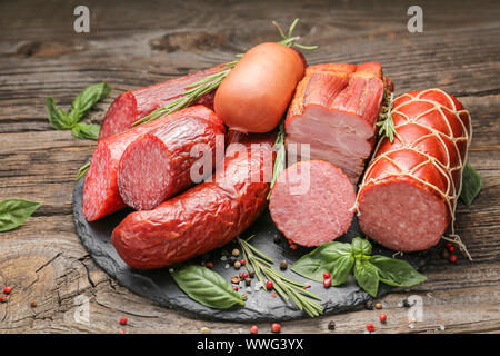 Schiefer Platte mit Auswahl an Würstchen auf hölzernen Tisch Stockfoto