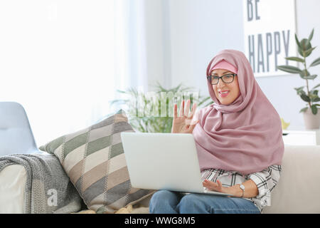 Schönen muslimischen Frau mittleren Alters mit Laptop zu Hause Stockfoto