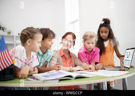 Kinder in der Nähe von ihrem Lehrer zeigt Ihnen Video auf Laptop Stockfoto