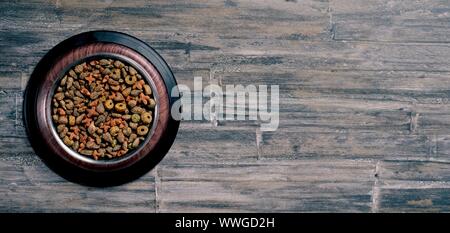 Schüssel mit Trockenfutter für Haustiere auf Holz- Hintergrund. Panoramabild mit kopieren. Stockfoto