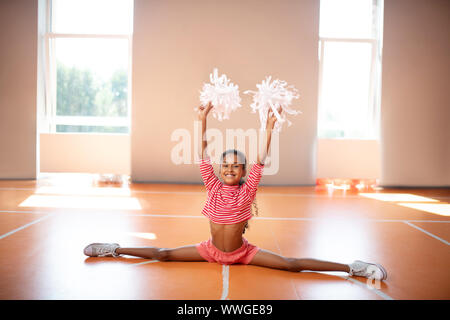 Dunkel - wenig Cheerleader tun leg Split beim Üben gehäutet Stockfoto