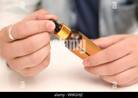 Bild des Mannes Tropfen Medizin Flasche in der Hand halten. Auf weissem Hintergrund. Stockfoto