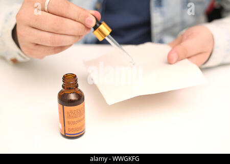 Bild des Mannes Tropfen Medizin Flasche in der Hand halten. Auf weissem Hintergrund. Stockfoto